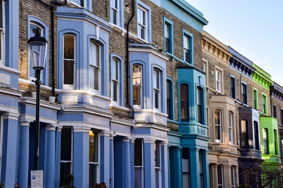 A row of Victorian-style terraced flats constructed with grey stone and white trim, situated along Bermondsey Street. The image shows a well-maintained grassy area in the foreground, with leafless tre